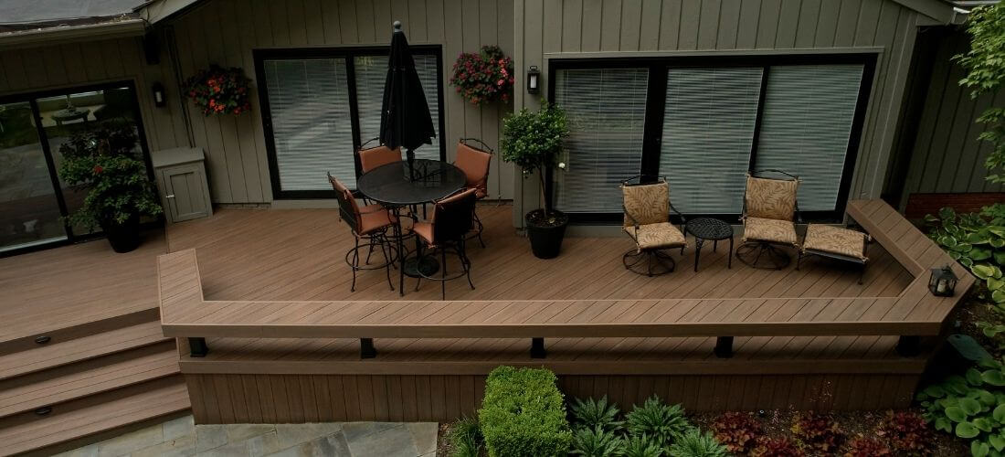 Prostorná terasa z PVC prken s jídelním a relaxačním koutem u domu.